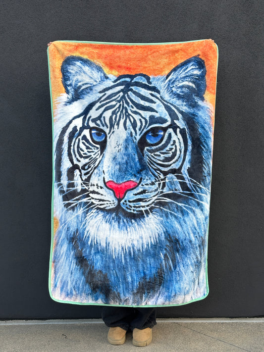 Full front view of RTEM’s Adorable Courage white tiger throw blanket, held upright against a dark wall. The original artwork features a blue-eyed white tiger with a bright pink nose, detailed white and blue fur, and an orange background.